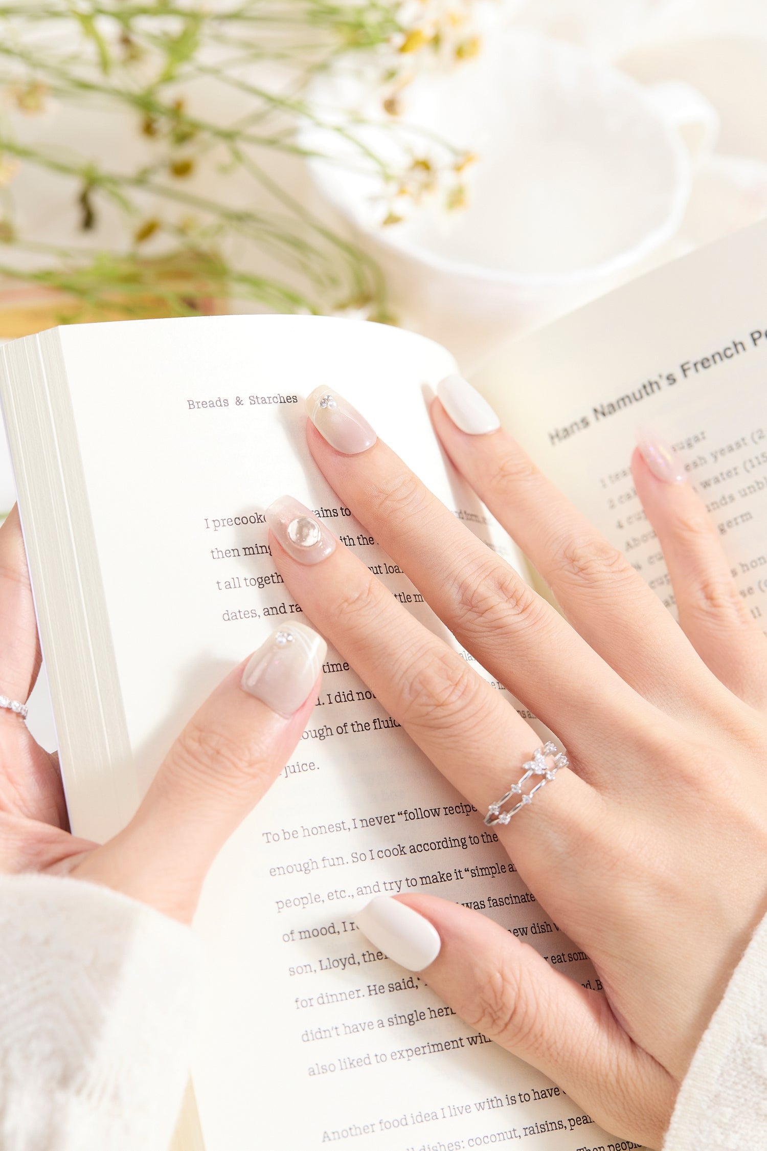 ootd.nail グレージュ × シルバーパーツ ジェルネイルチップ 着用イメージ｜透明感グレージュに大きめメタルチャームとパール風ストーンが輝く大人フェミニンデザイン。読書シーンにも馴染む上品ネイル。