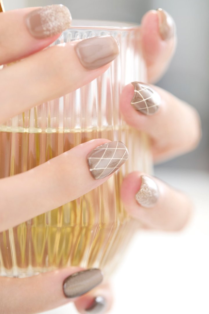 落ち着いたブラウン系デザインのリユーザブルネイルを装着した手元のアップ写真｜キルティング風アートとマグネットカラーが大人可愛い指先を演出。