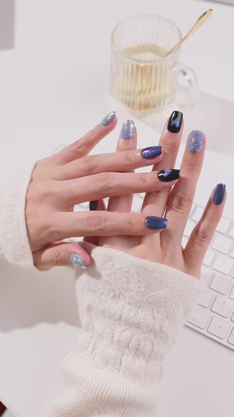 「ブルーマグネット×ブラックハートのジェルネイルチップを指先に着けた手元short movie。オーロラフレークのブルーネイルが光に輝くリユーザブルネイルデザイン」